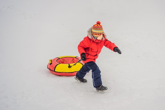 Foto niño divirtiéndose en un tubo de nieve niño montando un tubo diversión de invierno para niños