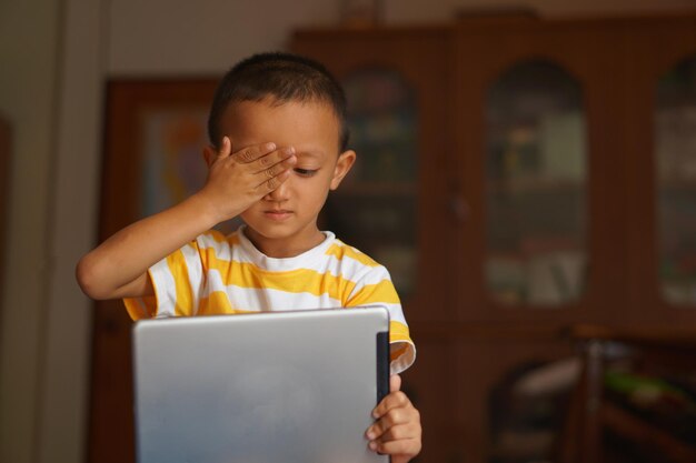 Niño con dolor de ojos por mirar la computadora