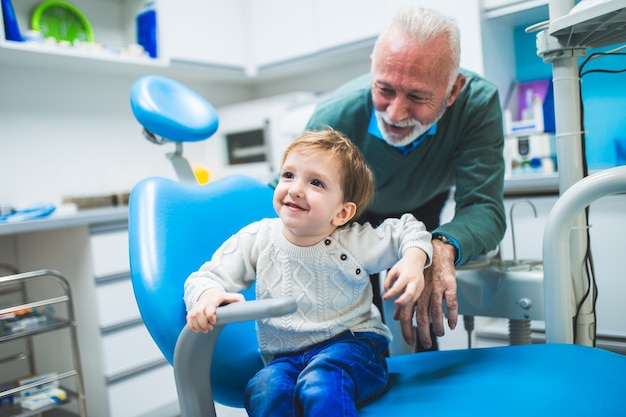 Niño de dos años con su abuelo por primera vez en el sillón dental.