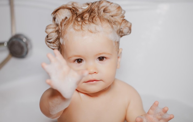 Niño en la ducha niño gracioso bañado en espuma y lavándose en la bañera en casa niño en la bañera con gripe