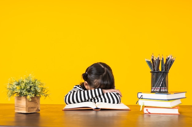 Niño duerme en la mesa con pila de libros