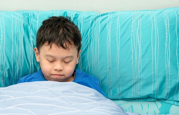 El niño duerme la siesta en una almohada cómoda con la luz del sol en la mañana, cara feliz y fresca