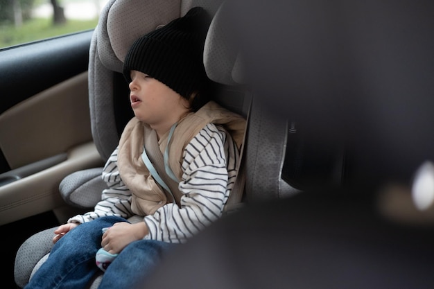 Niño durmiendo en el asiento elevado del arnés en un asiento de seguridad para niños