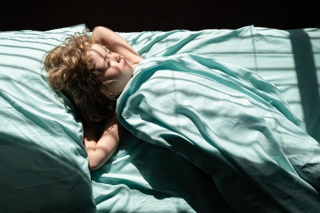 Niño durmiendo en la cama en el dormitorio en casa