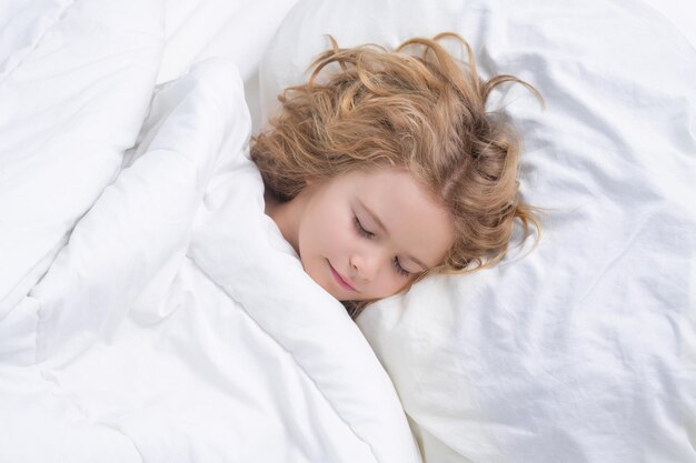 Niño durmiendo en una cómoda cama blanca hermosa cara de rubia caucásica niño durmiendo en la cama dulces sueños