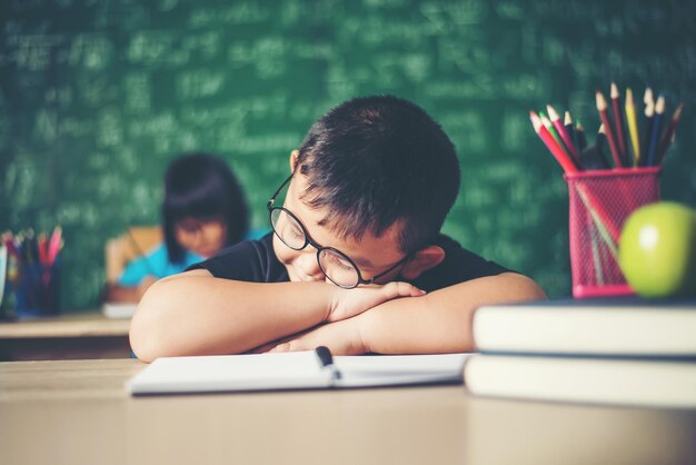 Niño durmiendo en los libros en el aula