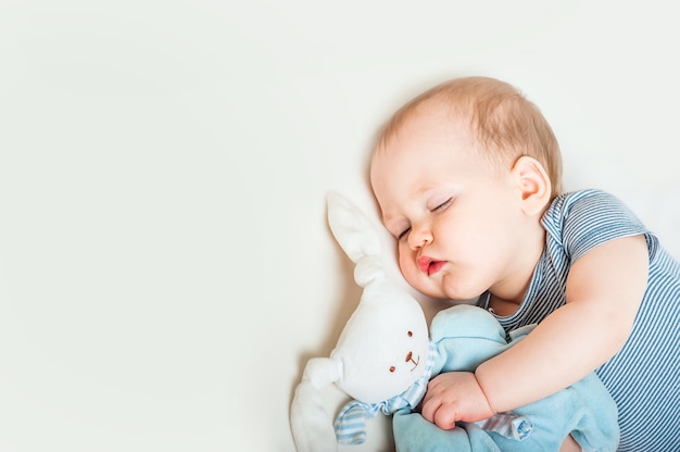 Niño durmiendo con liebre de juguete en la cama closeup Concepto de sueño saludable para bebés y espacio de copia