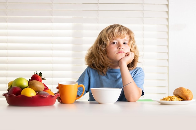 Niño en edad escolar desayunando antes de la escuela retrato de niño sentado en el escritorio en la cocina de casa tiene delicioso