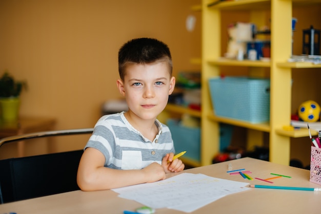 Foto un niño en edad escolar hace la tarea en casa. entrenamiento en la escuela.