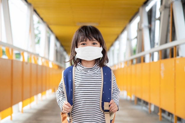 Niño en edad escolar con mascarilla durante el brote de coronavirus y gripe