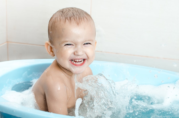 Niño en edad preescolar chico guapo bañándose en el baño limpio e higiénico