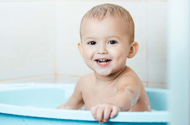 Niño en edad preescolar chico guapo bañándose en el baño limpio e higiénico