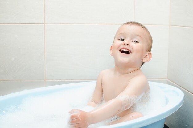 Niño en edad preescolar chico guapo bañándose en el baño limpio e higiénico