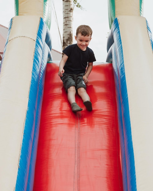 un niño en edad preescolar se desliza por un tobogán en un trampolín