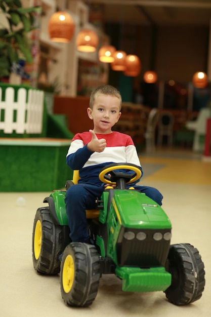 Un niño en edad preescolar que conduce su coche de juguete en un centro de entretenimiento para niños.