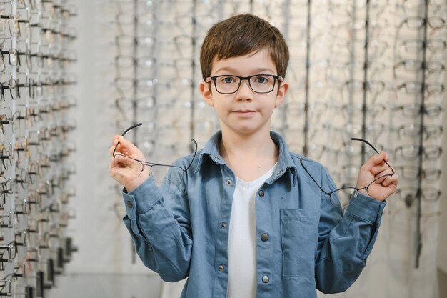 Foto niño eligiendo gafas en la tienda de óptica