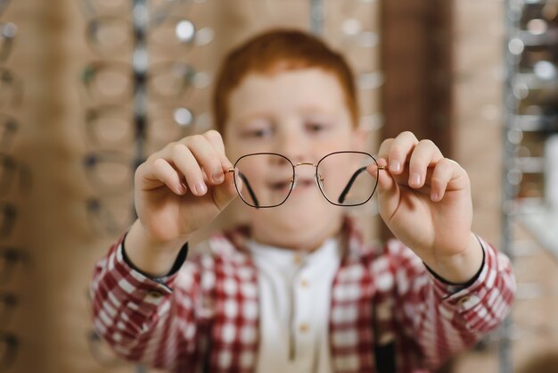 Niño eligiendo gafas en la tienda de óptica.