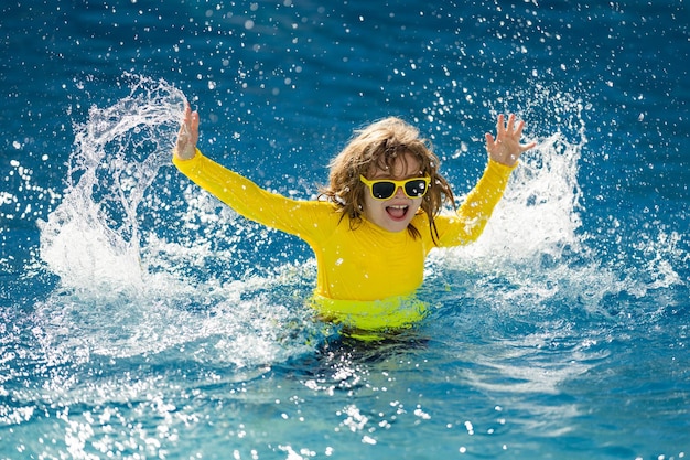 Niño emocionado nadando niño pequeño jugando en el agua azul de la piscina en un resort tropical en el