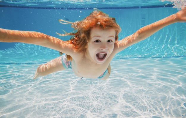 Niño emocionado nadar bajo el agua en la piscina