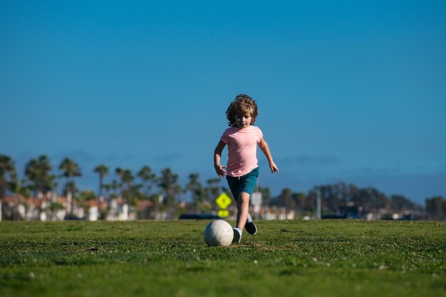 Niño emocionado pateando la pelota en el césped al aire libre fútbol niños niños jugar al fútbol los niños juegan así que...