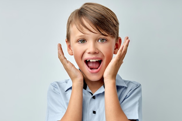 Niño emocional asombrado tocar la cara con la boca abierta aislado fondo de color gris. Adorable joven en estado de shock, mirando a la cámara con incredulidad. Conmoción, asombro, concepto sorpresa.