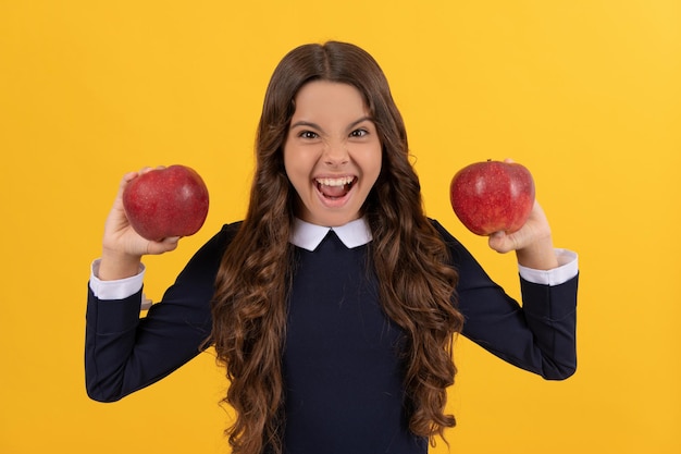 Niño emocional sostenga manzana de vitamina roja para el almuerzo sobre fondo amarillo con dientes