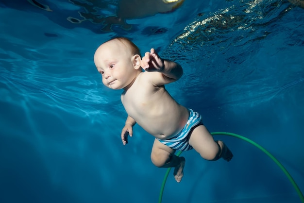 Un niño encantador aprende a nadar bajo el agua en una piscina infantil