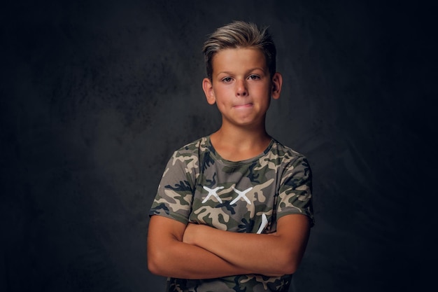 Un niño encantador con un bonito peinado posa sobre un fondo oscuro en el estudio fotográfico.