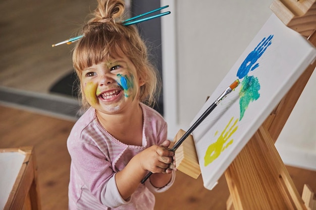 Foto niño encantador dibuja y tiñe todo con pinturas