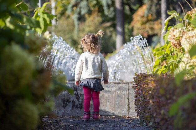 niño encantador en el parque con fuentes al fondo. día de verano