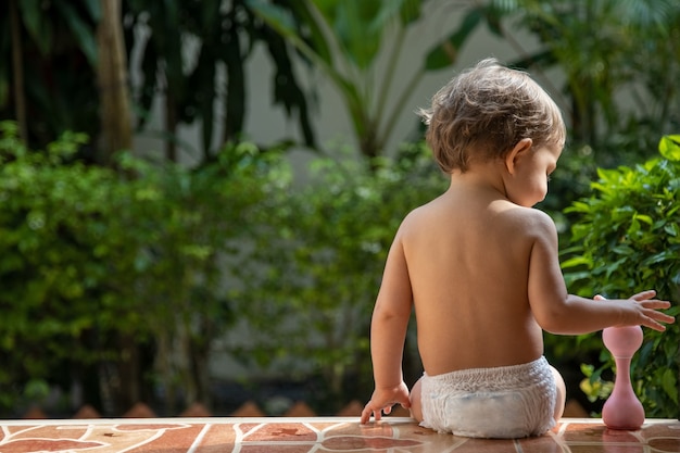 Un niño encantador se sienta en los escalones de una casa en la vista posterior de la luz del sol