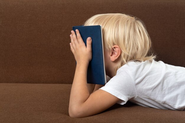 Niño se encuentra en el sofá con el libro en la cara