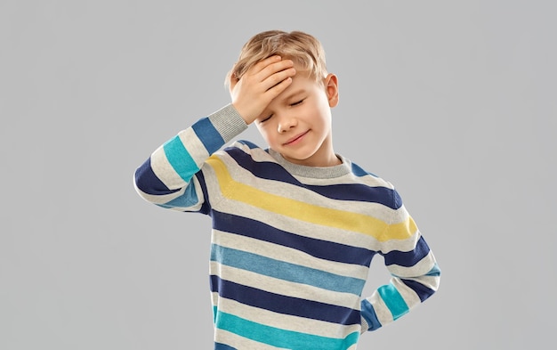 niño enfermo con camiseta roja sufriendo de dolor de cabeza