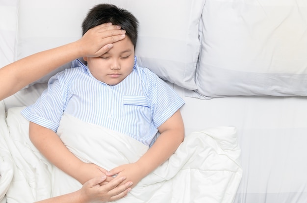 Niño enfermo con fiebre y enfermedad en la cama,