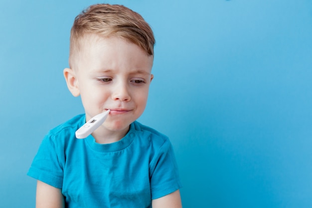 Niño enfermo con un termómetro, midiendo la altura de su fiebre