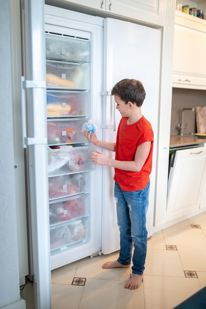 Niño enfocado eligiendo alimentos del congelador