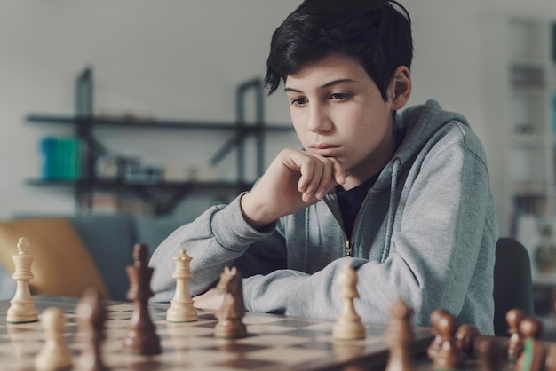 Niño enfocado jugando al ajedrez en casa