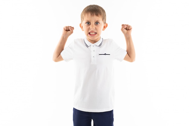 Niño enojado con flequillo en una camiseta blanca sobre un fondo blanco con espacio de copia