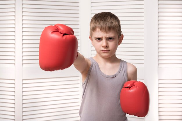 Niño enojado en guantes de boxeo rojos.