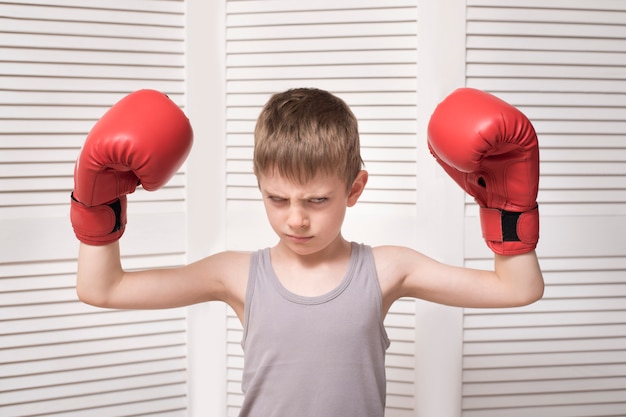 Niño enojado en guantes de boxeo rojos.