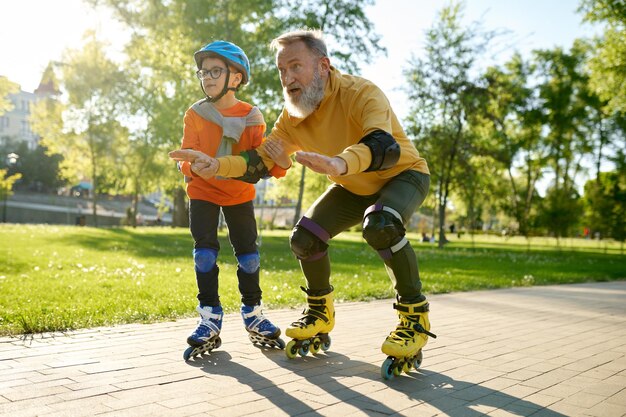 Foto niño enseñando a su padre a patinar en el parque hijo ayudando a papá a patinar de la mano