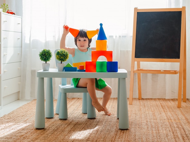 El niño se entrega a jugar en la habitación. Preescolar, jardín de infantes, 3 años