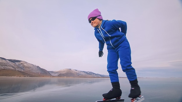 El niño entrena en patinaje de velocidad profesional sobre hielo La niña patina en el invierno en ropa deportiva traje de gafas deportivas Cámara lenta al aire libre