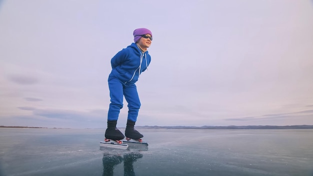 El niño entrena en patinaje de velocidad sobre hielo El atleta al principio en una postura deportiva La niña patina en invierno con ropa deportiva gafas deportivas Niños patinaje de velocidad pista corta larga Al aire libre