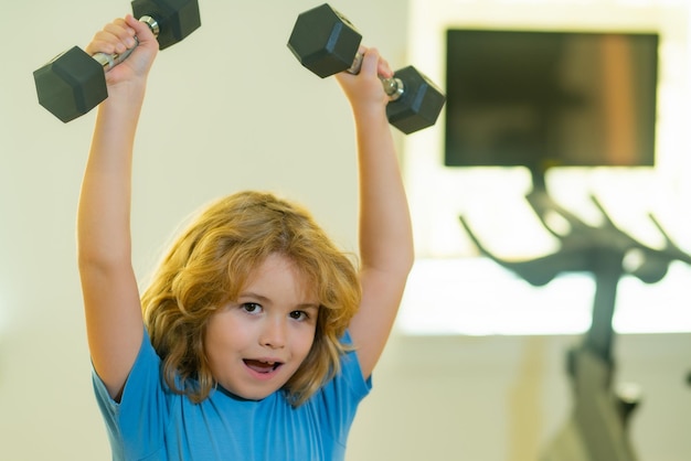 Foto niño entrenamiento niño en gimnasio lindo niño pequeño haciendo ejercicios con pesas retrato de niño deportivo con pesas niño feliz niño ejercicio actividades saludables estilo de vida de los niños
