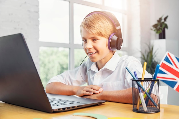 Niño entusiasta con auriculares estudiando inglés en línea