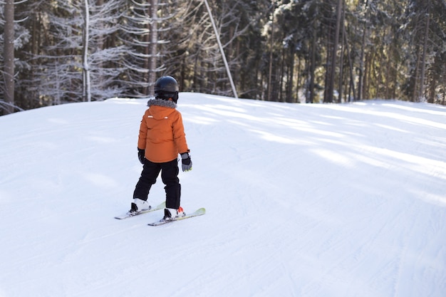 Un niño con equipo está esquiando en una pendiente nevada.