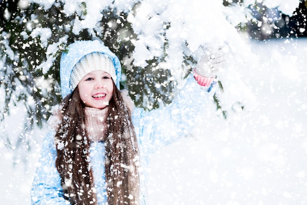 Un niño es feliz sosteniendo una rama nevada de abeto