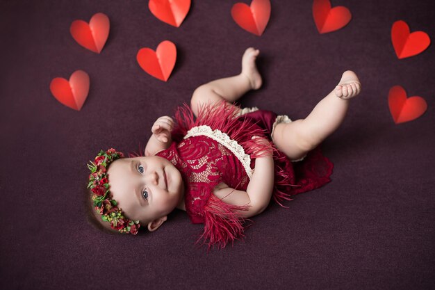 El niño es una niña sobre un fondo burdeos con corazones Día de San Valentín Día de San Valentín