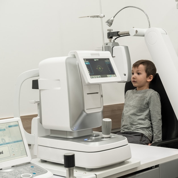 El niño es el paciente a la recepción en el médico oftalmólogo Equipo oftalmológico de diagnóstico